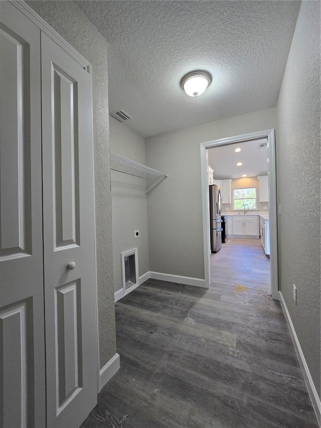 washroom with electric dryer hookup, visible vents, wood finished floors, and laundry area