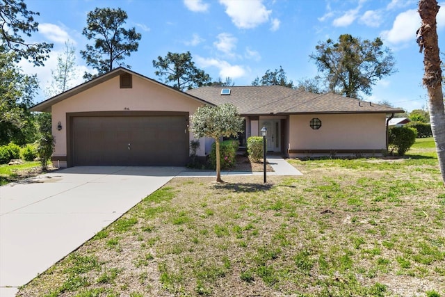 single story home with a front lawn, an attached garage, driveway, and stucco siding