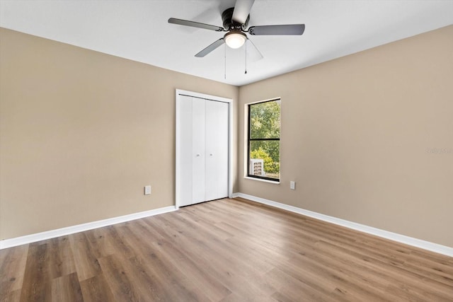 unfurnished bedroom featuring a closet, a ceiling fan, baseboards, and wood finished floors