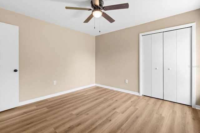 unfurnished bedroom with ceiling fan, a closet, baseboards, and light wood-style flooring