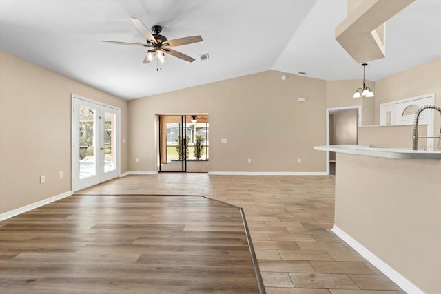 unfurnished living room featuring visible vents, light wood-style flooring, ceiling fan with notable chandelier, french doors, and lofted ceiling