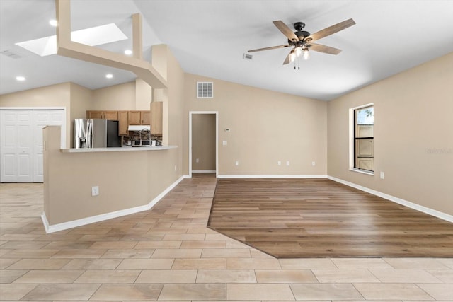 unfurnished living room with visible vents, baseboards, a ceiling fan, and vaulted ceiling