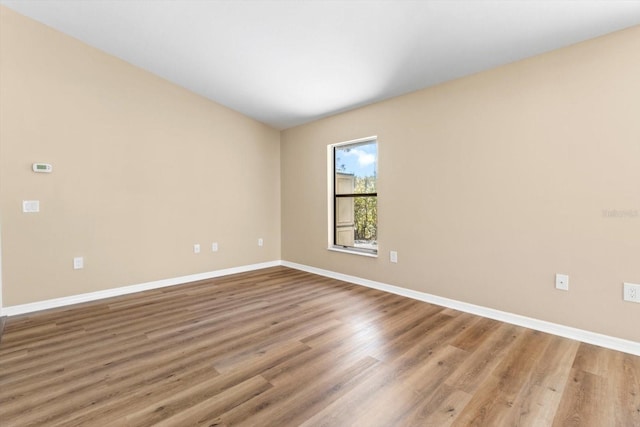 spare room with baseboards and wood finished floors