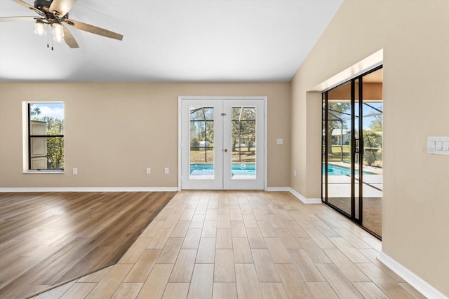 unfurnished room with light wood finished floors, baseboards, lofted ceiling, french doors, and a ceiling fan