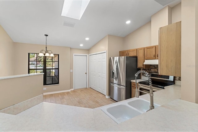 kitchen with vaulted ceiling with skylight, stainless steel appliances, light countertops, under cabinet range hood, and decorative light fixtures