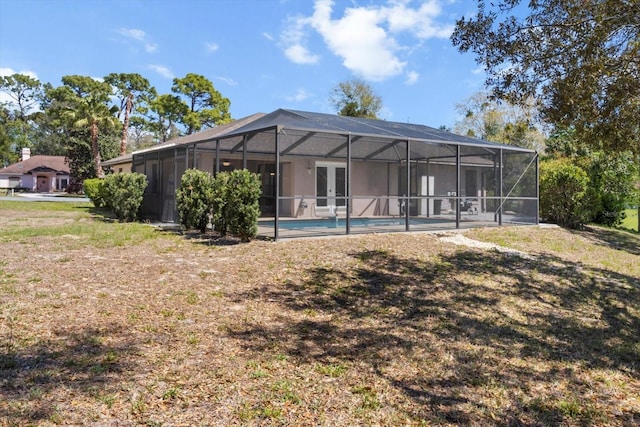 rear view of property featuring an outdoor pool, french doors, and glass enclosure