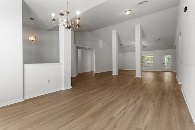 unfurnished living room with light wood finished floors, visible vents, a chandelier, and vaulted ceiling