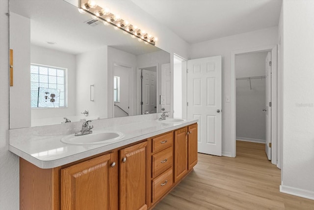 bathroom featuring double vanity, visible vents, wood finished floors, and a sink