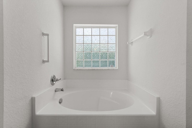 bathroom featuring a garden tub and a textured wall