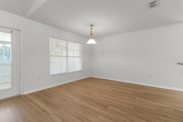 spare room featuring visible vents, light wood-style flooring, and baseboards