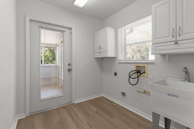 clothes washing area featuring baseboards, light wood-type flooring, hookup for a washing machine, cabinet space, and electric dryer hookup