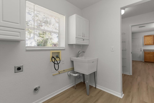 clothes washing area featuring electric dryer hookup, baseboards, cabinet space, and washer hookup