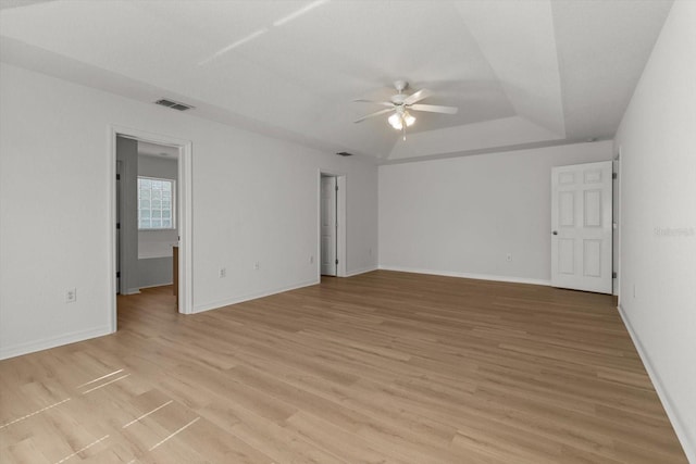 spare room featuring visible vents, baseboards, ceiling fan, a tray ceiling, and light wood-style flooring