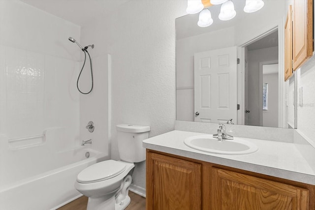 full bath featuring toilet,  shower combination, vanity, and a textured wall