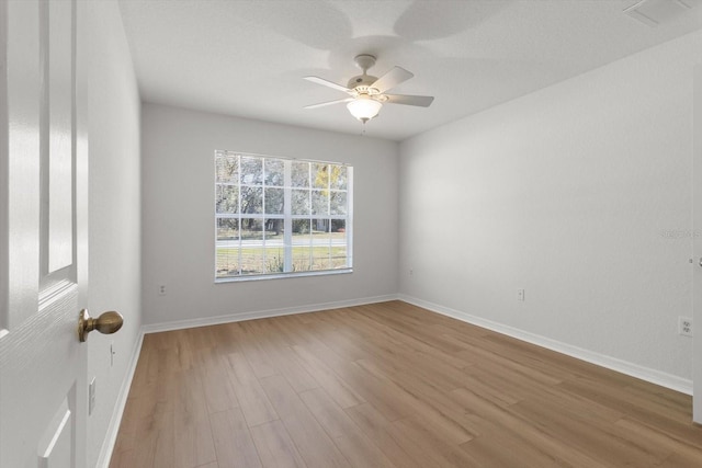 unfurnished room with ceiling fan, visible vents, baseboards, and wood finished floors