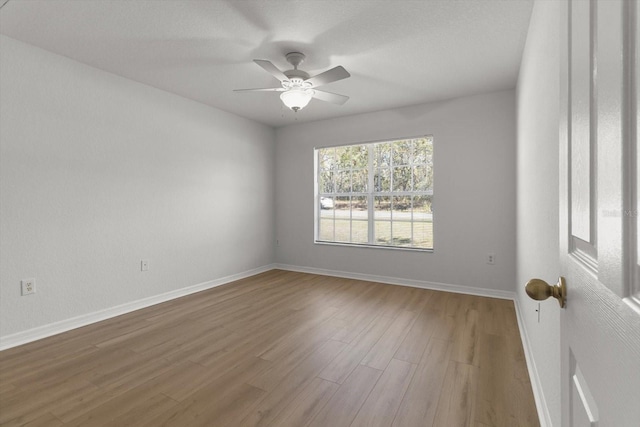 empty room with wood finished floors, baseboards, and ceiling fan