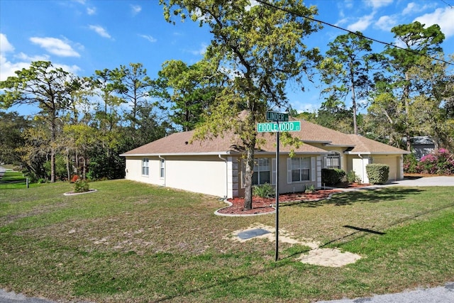 view of front of home with a front yard, a garage, driveway, and stucco siding