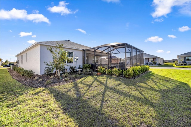 rear view of property featuring a yard, a lanai, and stucco siding