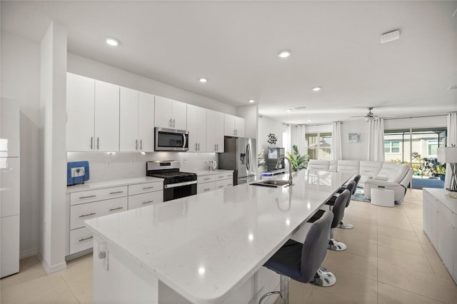 kitchen featuring a breakfast bar area, a sink, a large island, appliances with stainless steel finishes, and tasteful backsplash