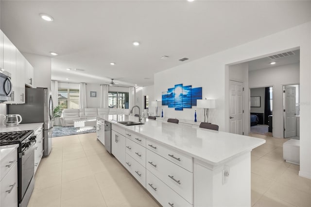 kitchen with visible vents, a large island, a sink, open floor plan, and stainless steel appliances