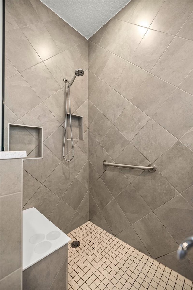 bathroom featuring a textured ceiling and tiled shower