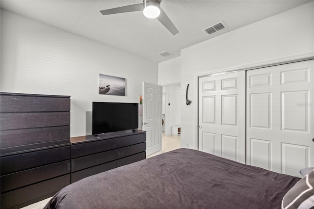 bedroom featuring a closet, visible vents, a textured ceiling, and a ceiling fan