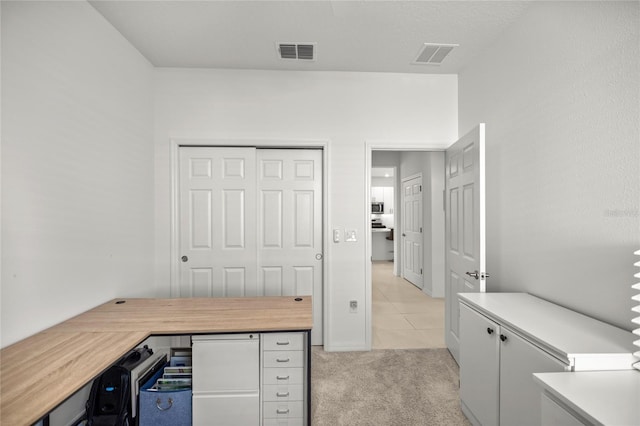 home office featuring light tile patterned floors, light colored carpet, and visible vents