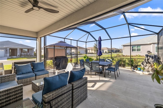 view of patio featuring a residential view, glass enclosure, an outdoor hangout area, outdoor dining space, and a ceiling fan