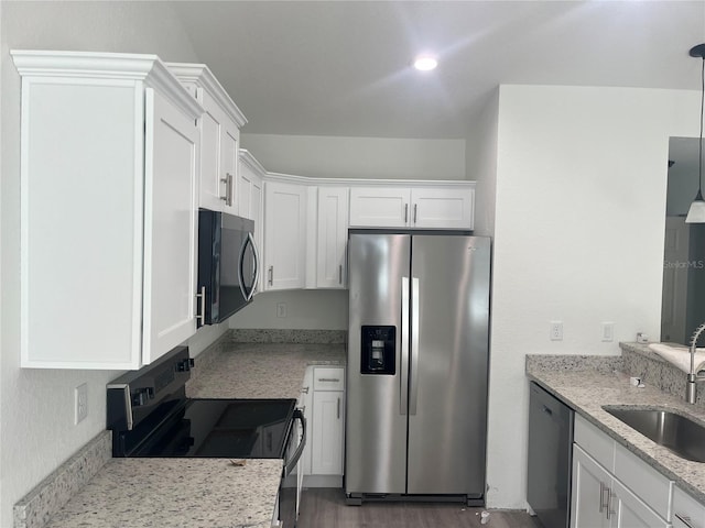 kitchen with a sink, stainless steel appliances, light stone countertops, and white cabinetry