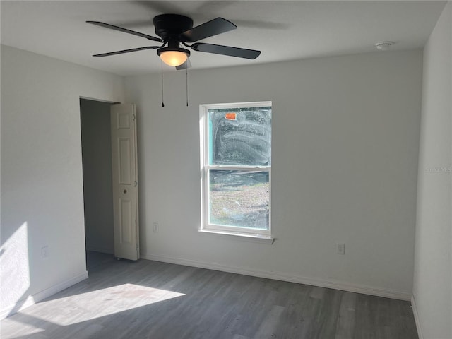 empty room featuring wood finished floors, baseboards, and ceiling fan