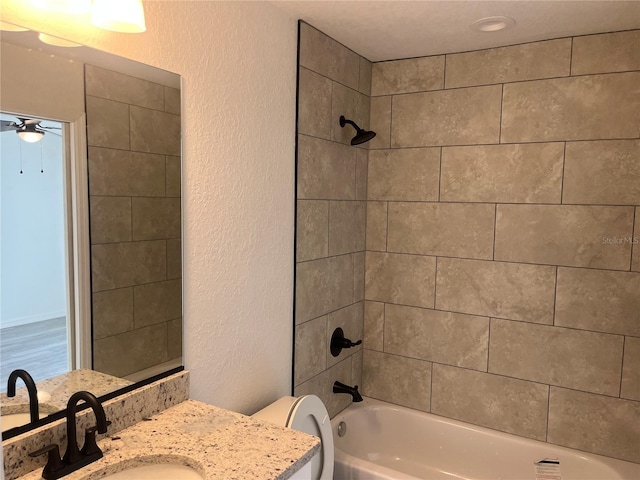 full bathroom featuring toilet, a ceiling fan, bathtub / shower combination, vanity, and a textured wall