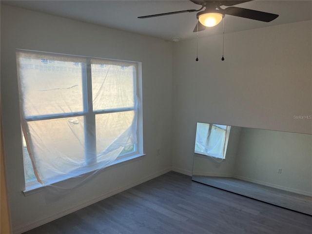 spare room featuring wood finished floors, baseboards, and ceiling fan