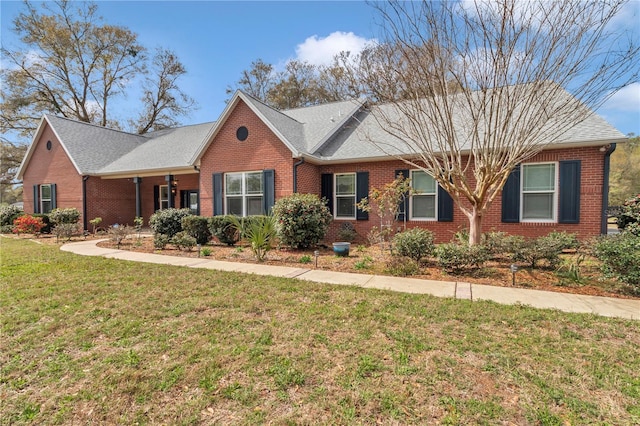 single story home featuring brick siding, a front lawn, and roof with shingles