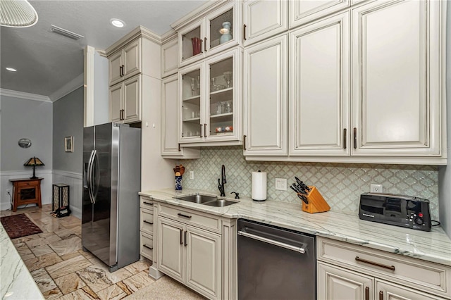 kitchen featuring visible vents, cream cabinetry, ornamental molding, a sink, and appliances with stainless steel finishes