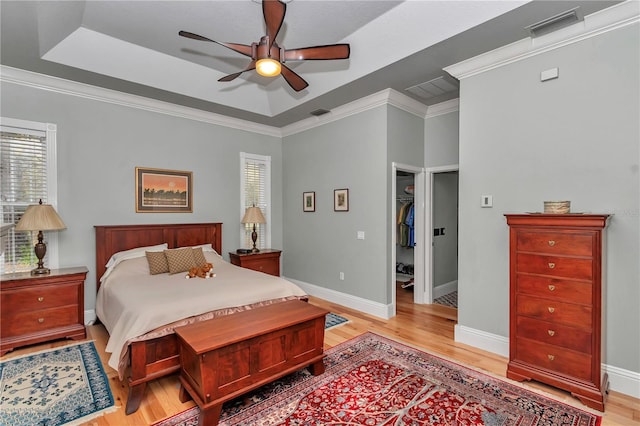 bedroom with a tray ceiling, visible vents, and light wood finished floors