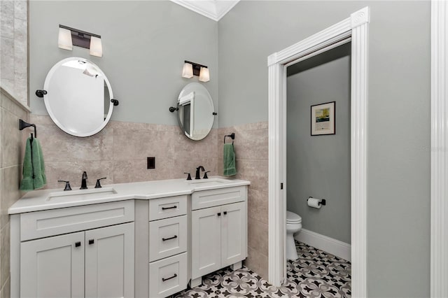 full bathroom featuring tile walls, toilet, double vanity, and a sink