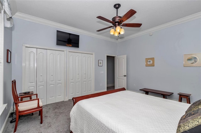 carpeted bedroom with baseboards, a ceiling fan, crown molding, and multiple closets