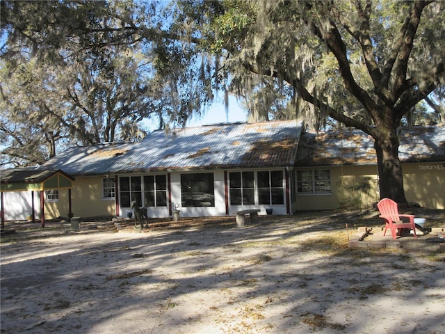 back of house featuring metal roof, a sunroom, and entry steps