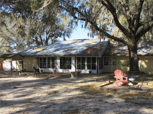 back of house with metal roof, a patio, and a sunroom