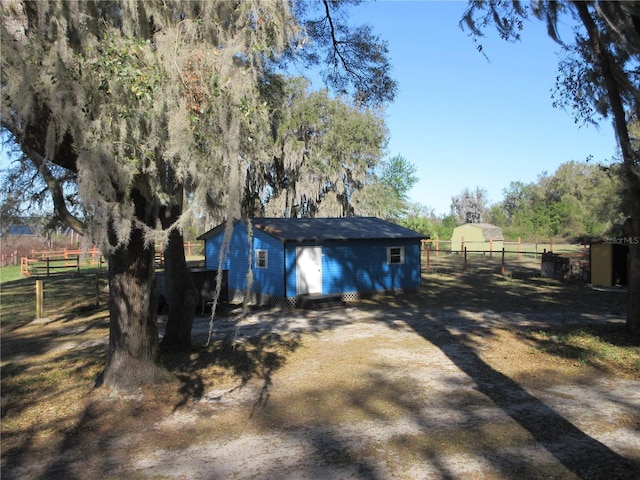 exterior space with a rural view, driveway, and fence