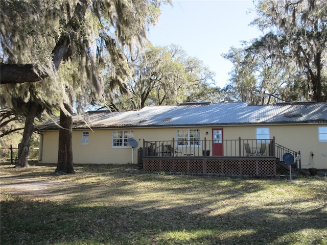 back of property featuring a wooden deck, metal roof, and a yard