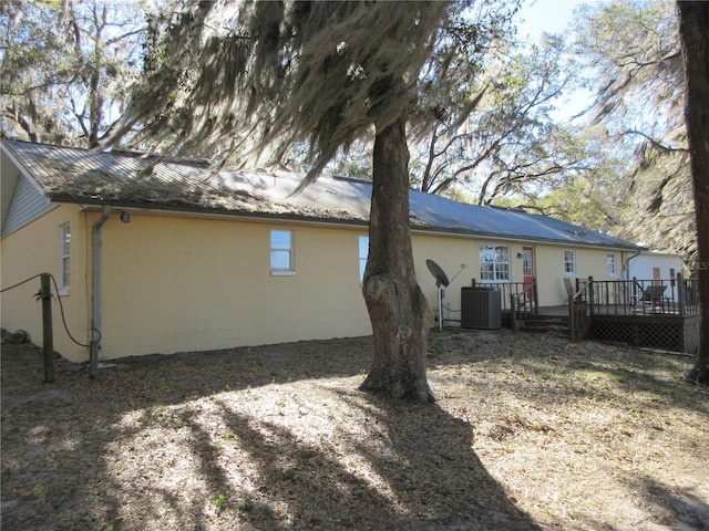 back of property featuring central AC, a deck, and metal roof