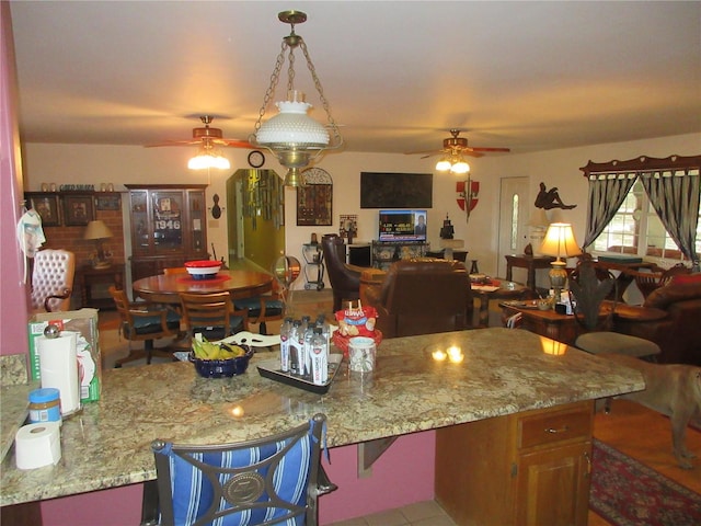 kitchen with light stone counters, open floor plan, and a ceiling fan