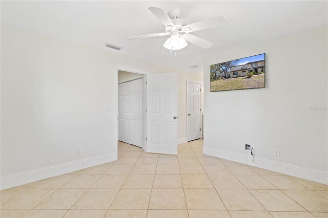 unfurnished bedroom featuring light tile patterned floors, baseboards, visible vents, and ceiling fan