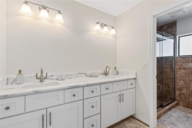 bathroom with a sink, a stall shower, and double vanity