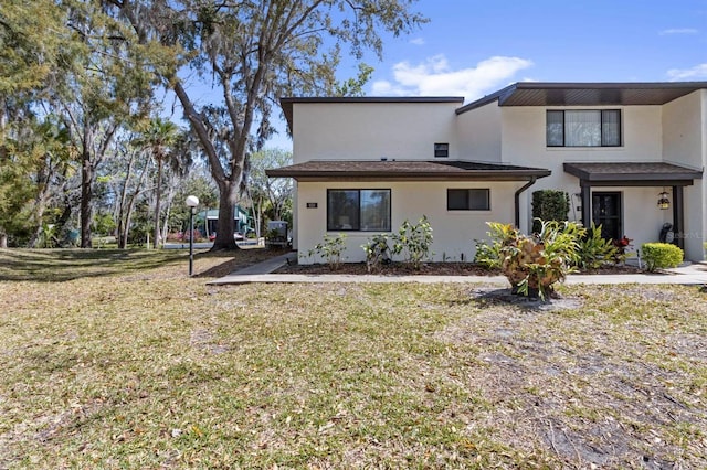 rear view of property featuring stucco siding and a lawn