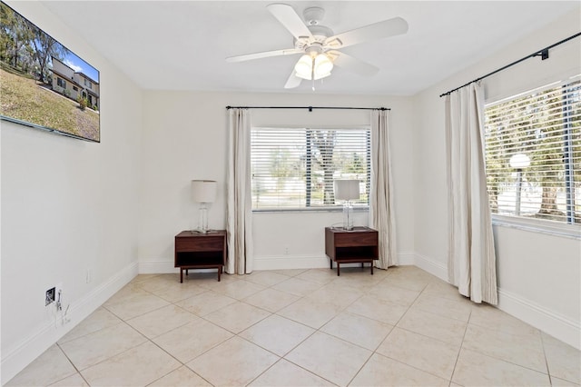 empty room featuring light tile patterned floors, a healthy amount of sunlight, baseboards, and a ceiling fan