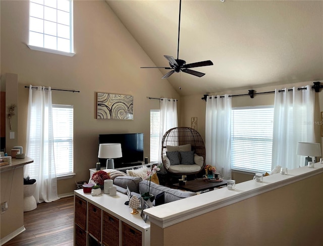 living area featuring baseboards, high vaulted ceiling, wood finished floors, and a ceiling fan