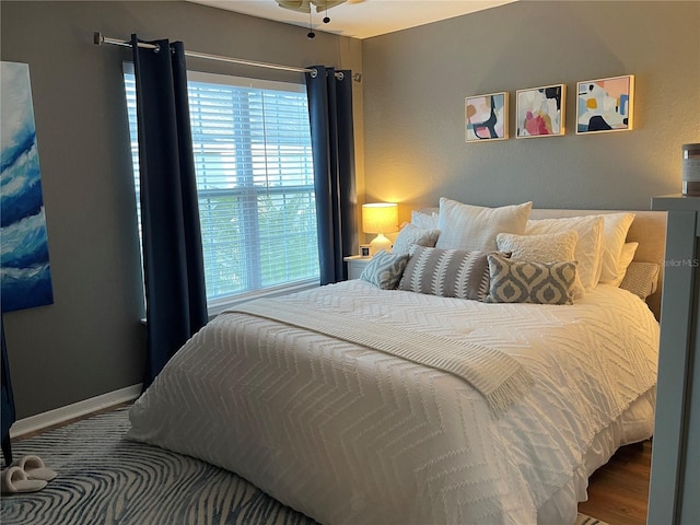 bedroom featuring baseboards, multiple windows, and wood finished floors