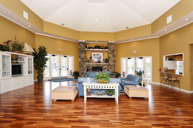 living room with a high ceiling, a stone fireplace, and wood finished floors